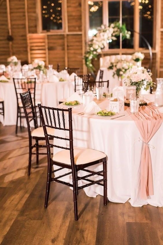 Classic Pink Wedding Table Decorations. Playful Pink Fall Wedding Guests sat at round tables with white tablecloths and pink runners in the authentic renovated dairy barn at this pink fall wedding