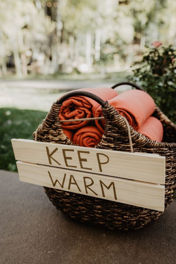 Adorable blanket basket for guest to keep warm at this outdoor wedding reception. Keep warm wedding blankets!